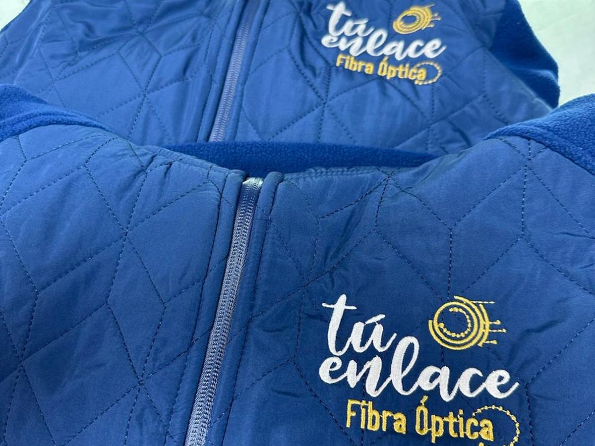 Chaquetas corporativas azules con el logo de Tú Enlace Fibra Óptica bordado, en la máquina del taller JAS