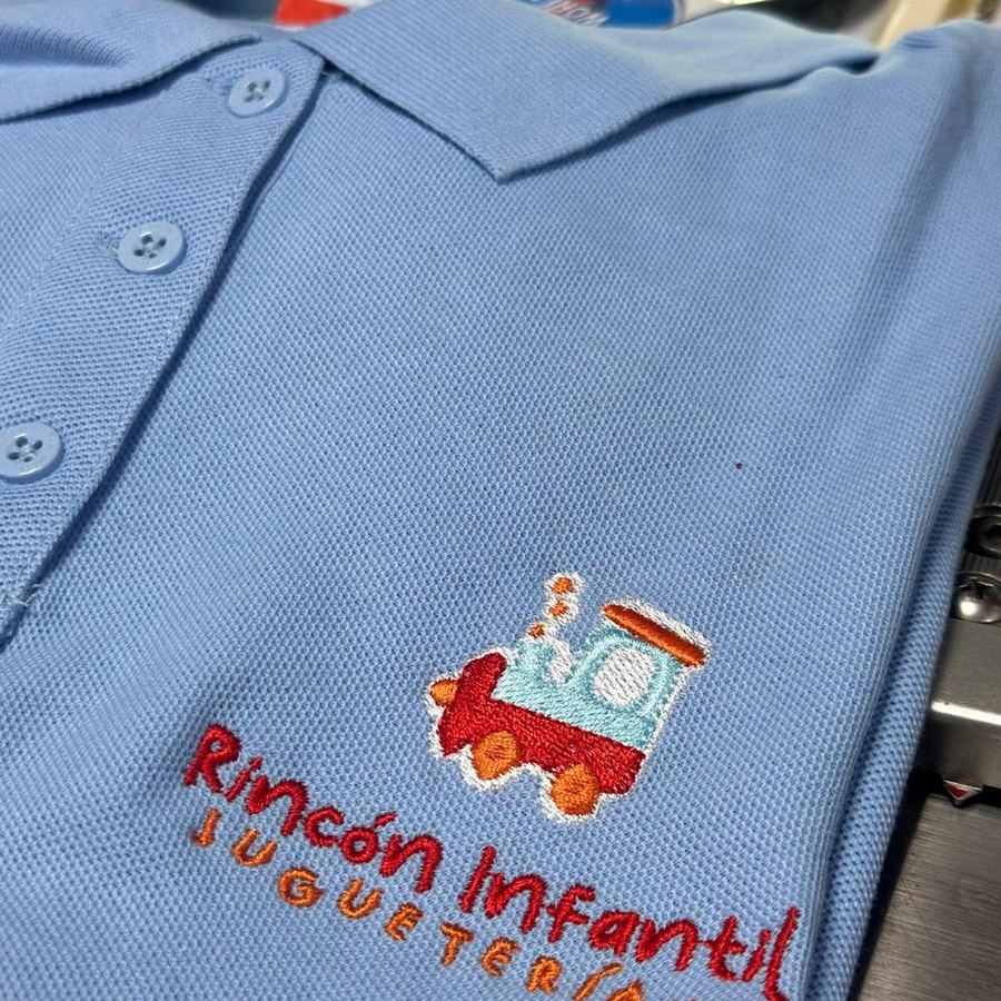 Polera piqué celeste con el logo Rincón Infantil Juguetería bordado a varios colores
