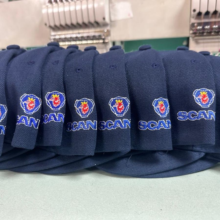 Fila de gorros azul marino con el logo Scania bordado